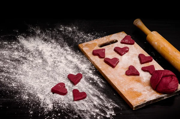 Kırmızı kalp çerez ve ahşap tahta üzerinde hamur bir parça, Sevgililer Günü için pişirme — Stok fotoğraf