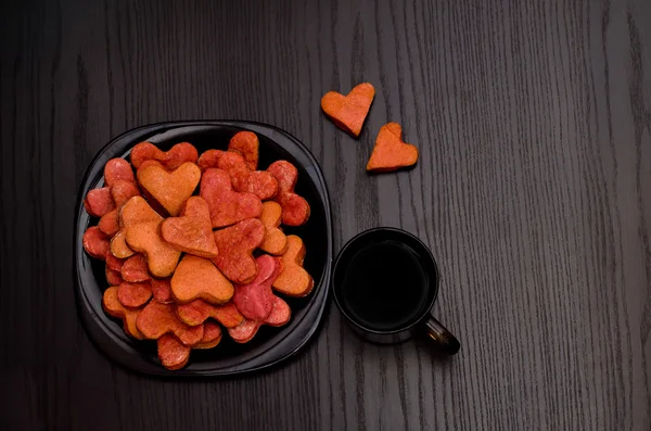 Red heart-shaped cookies on a black plate, coffee mug , Valentine's Day — Stok fotoğraf