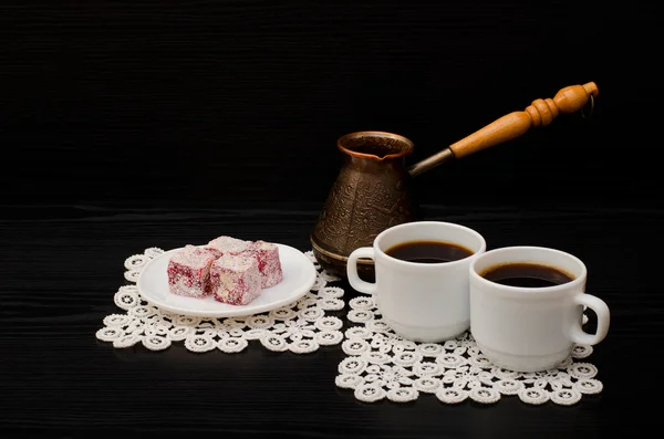 Two mugs of coffee, Turkish delight and cherry pots on a black background — Stock Photo, Image