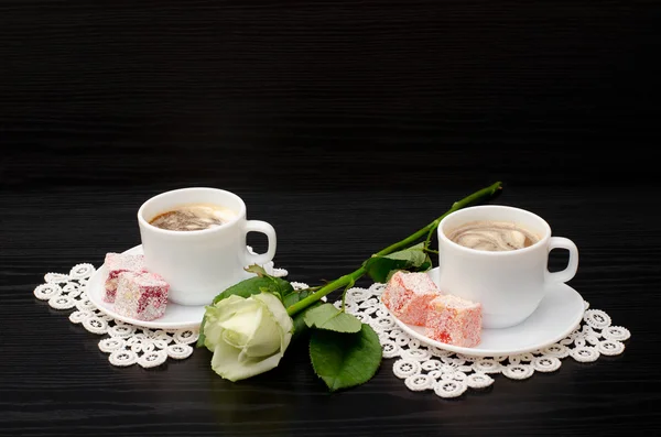 Coffee for two with oriental sweets, a white rose on a black background — Stock Photo, Image