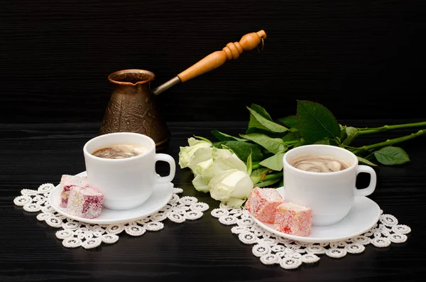 A couple cups of coffee with milk, Cezve, oriental sweets, a bouquet of white roses on a black background — Stock Photo, Image