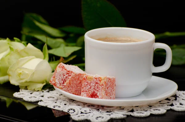 Side view of a coffee cup with milk close-up, oriental sweets. smartphone, white roses on a black background — Stock Photo, Image