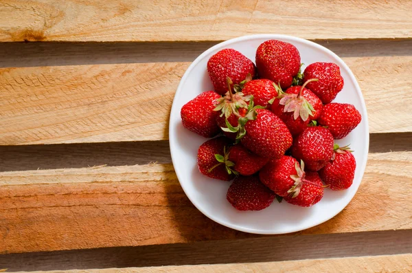 Placa con fresas sobre un fondo de tablones de madera, vista superior, mañana — Foto de Stock