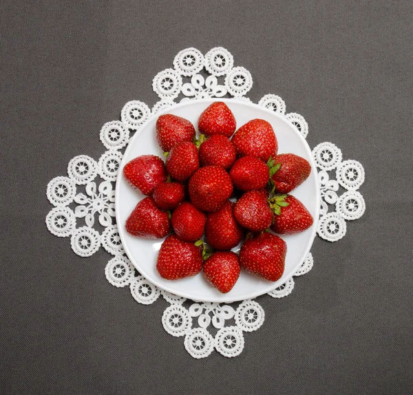 Fresas maduras en un plato sobre un fondo gris, vista superior — Foto de Stock