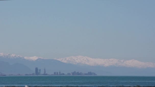 Uitzicht vanaf de zee naar de stad Batumi op de achtergrond van besneeuwde bergen en een wolkenloze hemel. Georgië. — Stockvideo