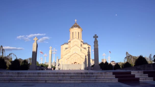 Camine hasta la entrada de la iglesia de Sameba sobre un fondo de cielo azul, temprano en la noche — Vídeo de stock