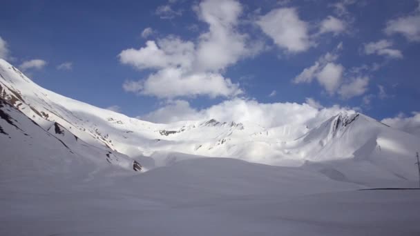 Zasněžené hory na pozadí mraků a modré oblohy z okna auta. Kavkaz, Gruzie. — Stock video