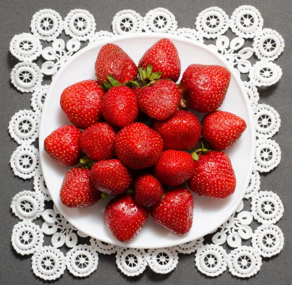 Bayas fresas maduras en el plato en servilleta de encaje, vista superior, fondo gris — Foto de Stock