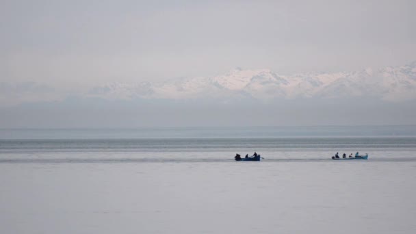 Motor e barco a remo flutuando em um fundo de montanhas cobertas de neve. Black Sea Batumi, Geórgia . — Vídeo de Stock