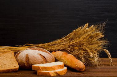 Beyaz ve çavdar ekmeği, bir somun, ahşap masa, siyah arka plan, metin için yer bir demet