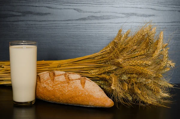 Um copo de leite, pão de trigo integral e um molho sobre um fundo escuro — Fotografia de Stock