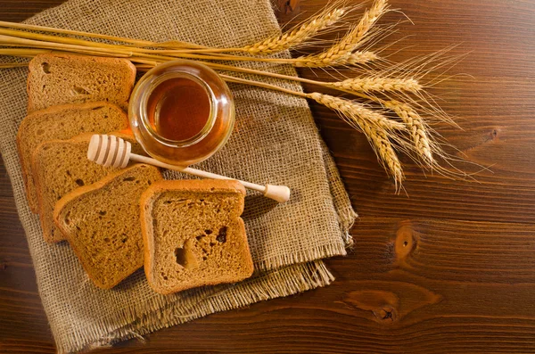 Банка с медом, ржаной хлеб, ложка меда и шипы на вретище — стоковое фото