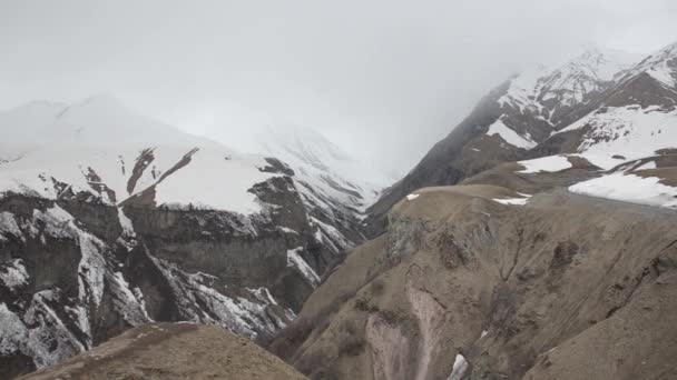 Canyon en met sneeuw bedekte bergen in de mist. Georgia, Caucasus. — Stockvideo