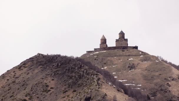 Gergeti Trinity Church in mountains against a white sky. Georgia, Caucasus. — Stock Video