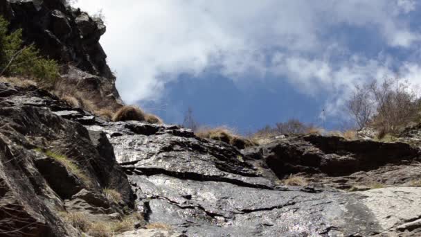 Dünne Wasserströme, die auf einem Hintergrund aus treibenden Wolken den Felsen hinunterfließen. Blick von unten. gveletskie Wasserfälle. Georgien, Kaukasus. — Stockvideo