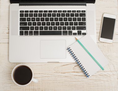 Bir dizüstü bilgisayar klavye, akıllı telefon, bir defter bir kalem ve bir fincan kahve ile Üstten Görünüm