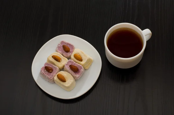 Top view of Turkish delight with almonds and cup of coffee, black table — Stock Photo, Image