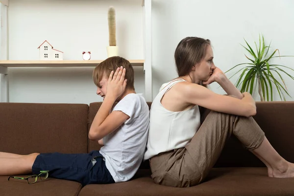 Mom and child are in quarrel. Mom and teenage son sit with their backs to each other and do not want to talk. Family conflict.