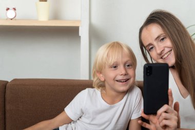Genç anne ve oğul akıllı telefona bakıp gülümseyin. Telefonda selfie..