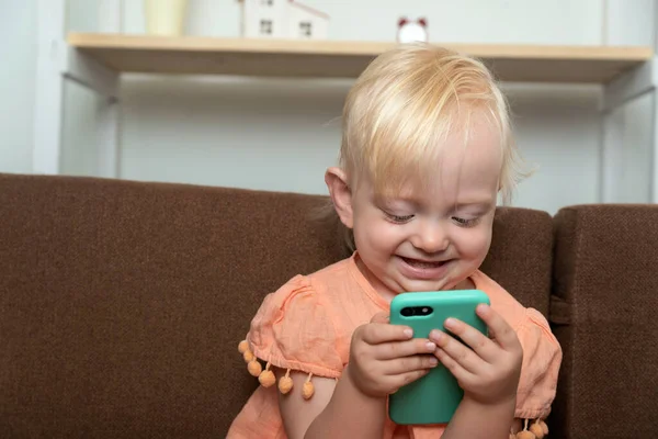 赤ちゃんはスマートフォンの画面と笑顔を見ています 子供は携帯電話で遊ぶ — ストック写真