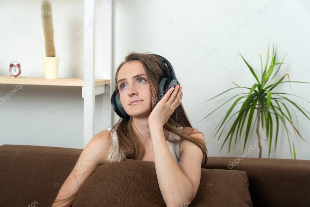 Beautiful young woman in headphones thoughtfully listens to music.