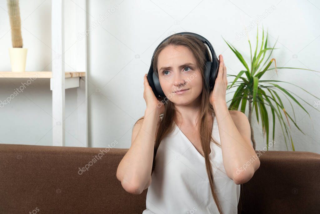 Girl at home with headphones listening to music audiobook podcasts.