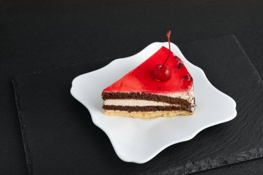 Beyaz tabakta kremalı kırmızı meyveli pasta. Siyah arkaplan