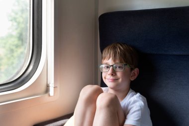 Gözlüklü çocuk kompartımanda oturuyor. Çocuklarla trenle seyahat etmek. Demiryolu yolculuğu.