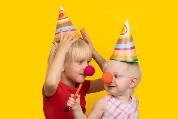 Gelukkige Kinderen Met Feestelijke Hoeden Een Rode Clownneus Gele Achtergrond — Stockfoto