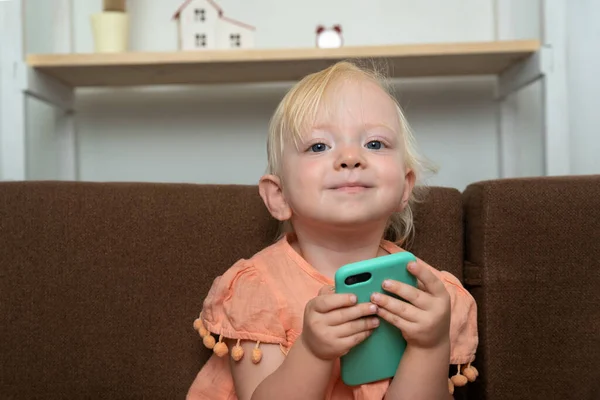 赤ちゃんは手に電話を持って笑っている スマートフォンを手にした子供の肖像 — ストック写真