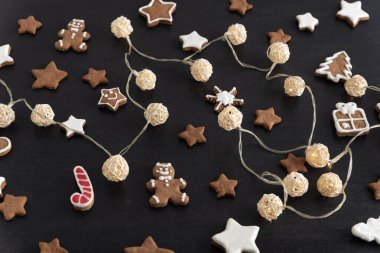 Noel kurabiyeleri yıldızları ve siyah arka planda çelenkler. Zencefilli ekmek..