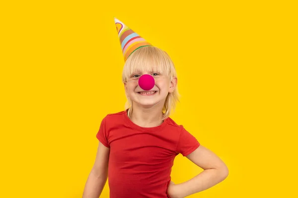 Parti Şapkalı Mutlu Sarışın Çocuk Kameraya Gülümseyen Kırmızı Palyaço Burunlu — Stok fotoğraf