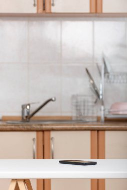 Mutfak masasında unutulmuş akıllı telefon. Mutfakta cep telefonu var..