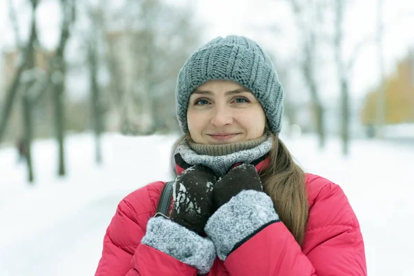 雪に覆われた公園の背景に帽子の若い女性の肖像画 — ストック写真