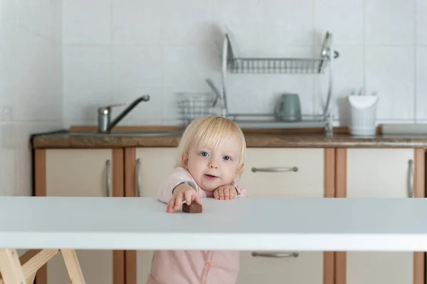 Nettes Blondes Mädchen Zieht Ihre Hand Süßigkeiten Auf Dem Tisch — Stockfoto