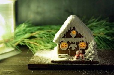 Spruce şubesinin arka planında zencefilli kek evi. Kış tatili modeli. Mutlu Noeller ve mutlu yıllar..