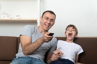 Baba ve oğul televizyon izliyor ve yüksek sesle gülüyorlar. Aile dostu ilişkiler