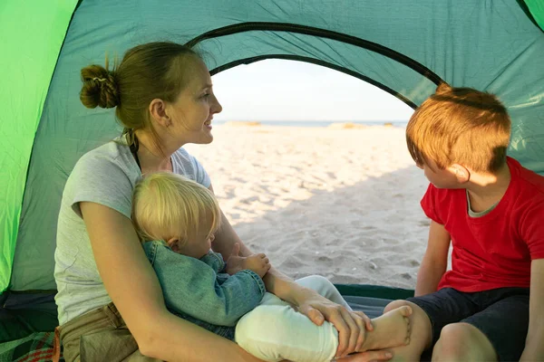 Happy family holidays in tent with child in nature. Concept of traveling, hiking, camping.