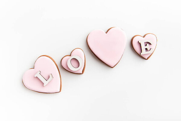 Gingerbread cookies in theart-shaped with white sugar icing on white background and inscription LOVE