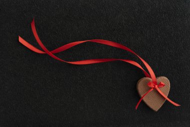 Siyah arka planda kırmızı kurdeleli kalp şeklinde zencefilli kurabiyeler. Anneler Günü. Kadınlar Günü. Sevgililer Günü.