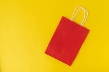Sarı arka planda kırmızı kese kağıdı. Alışveriş çantası. Üst Manzara. Uzayı kopyala Model