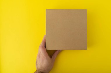 Sarı arka planda kare karton kutu. Uzayı kopyala Model