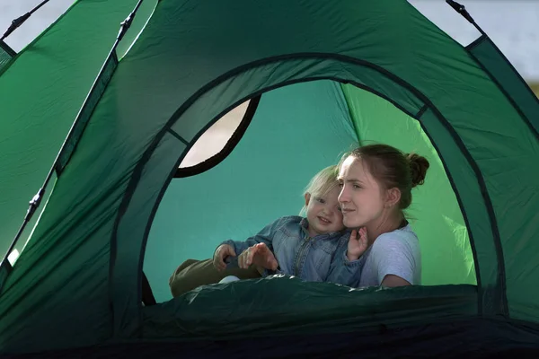 Mom and baby in big tourist tent. Camping with children.