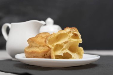 Havalı profiteroller, puflar, börekler, çay seti arka planında beyaz tabakta ekler-