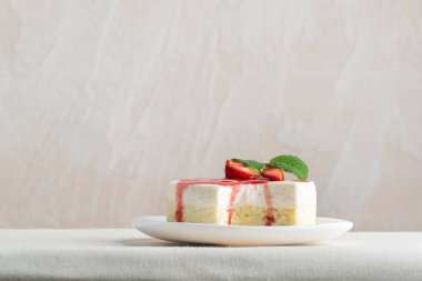 Taze çilekli nefis peynirli kek ve beyaz tabakta nane şekeri. Yan görünüm.