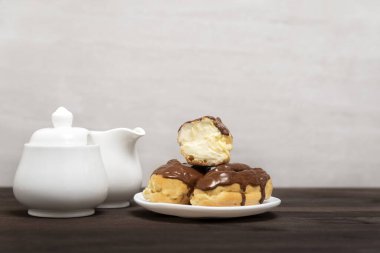 Beyaz tabakta tereyağlı kremayla çikolataya batırılmış ekler. Fransız tatlısı.