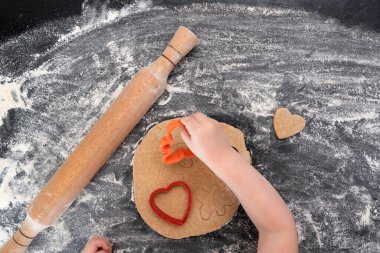 Çocuk kurabiye hazırlar. Çocuk elleri, hamurlu, oklavalı ve kurabiye kesicili.