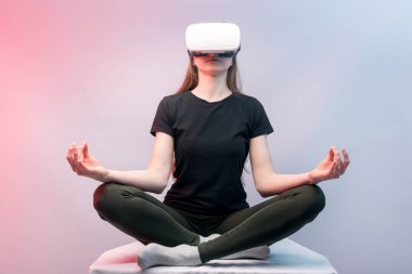 Sanal gerçekliği deneyimleyen bir kız. VR gözlüklü kadın meditasyon yapıyor.