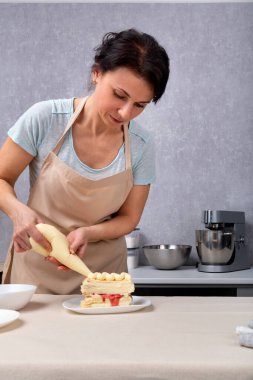 Kadın şef pastayı mutfak çantasıyla süslüyor. Dikey çerçeve.