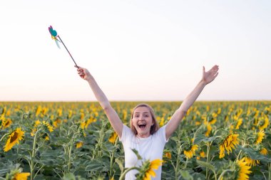 Neşeli mutlu kız ayçiçeği tarlasında yürüyor. Çılgın kadın dışarıda..